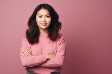 Obraz premium Portrait of a merry asian woman in her 20s with arms crossed over minimalist or empty room background