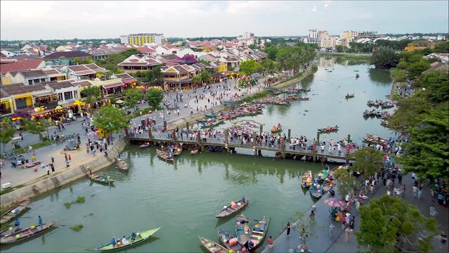 4K Aerial of Hoian, Vietnam. An Hoi Bridge. Night Time. Wide Stationary whilst tourist boats move around the river