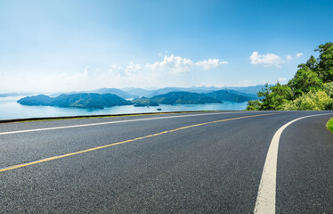 Asphalt highway road and lake with islands nature landscape on a sunny day. Beautiful coastline in...