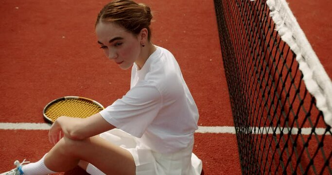 A Woman resting after play tennis on carpet court outdoors. Tennis match. Active leisure game. Weekend and Sunday activity for recreation. Sports active game with friends. Tennis player in action.