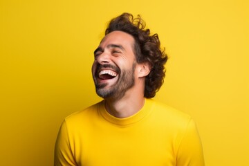 Portrait of a smiling man in his 30s laughing on solid color backdrop