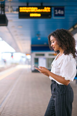 Businesswoman Commuting On Train Platform Using Mobile Phone For Travel Information Or Social Media