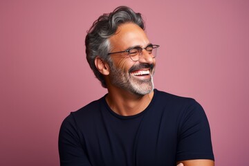 Fototapeta premium Portrait of a content man in his 50s laughing isolated on solid color backdrop