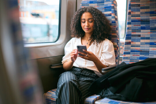 Businesswoman Commuting To Work On Train Sitting Checking Messages Or Social Media On Mobile Phone