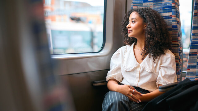 Businesswoman Commuting To Work On Train Sitting And Relaxing Looking Out Of Window