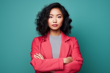 Obraz premium Portrait of a content asian woman in her 20s with arms crossed in front of solid color backdrop