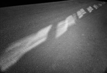 Black and white diagonal light spots on asphalt