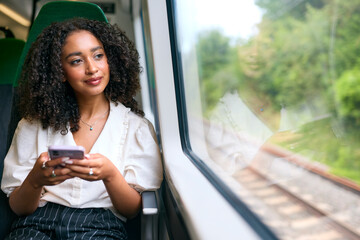 Businesswoman Commuting To Work On Train Sitting Checking Messages Or Social Media On Mobile Phone