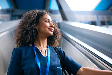 Female Doctor Or Nurse Commuting On Escalator At Railway Station To Train Platform