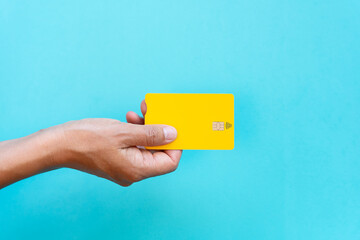 Concept contact less use. Hand view from above taking yellow credit card on blue background