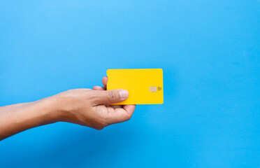 Woman hand holding yellow credit card with contact less symbol on blue background