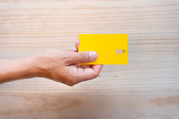 Top view composition on hand holding yellow credit card with contact less symbol and chip on...