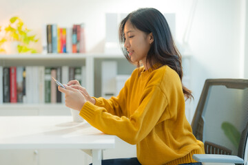 Young asian woman using smartphone in modern home office