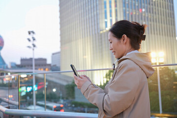Young Woman Using Smartphone in Urban Twilight