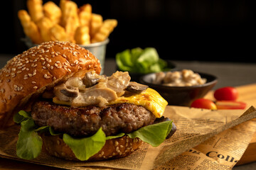 On rustic background, close-up reveals gourmet cheeseburger topped with mushrooms and lettuce,...
