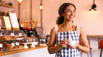Confident Young Woman Wearing Apron Working In Coffee Shop Or Cafe