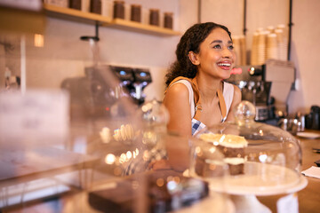 Confident Young Woman Wearing Apron Working Behind Counter In Coffee Shop Or Cafe
