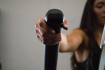 Detail of the hand of a young and beautiful brunette woman training on an elliptical treadmill in a...