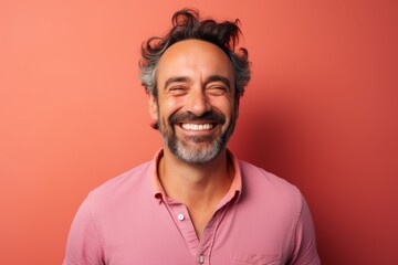 Portrait of a joyful man in his 40s smiling at the camera in solid pastel color wall
