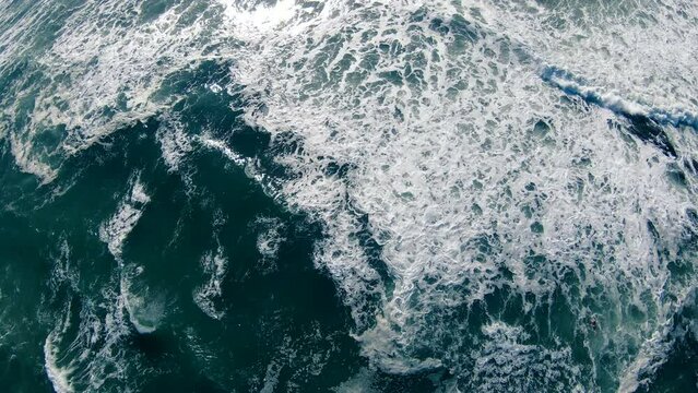 Looking down on the rough waves in the ocean as the surfers wait for a wave
