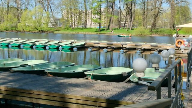 A row of boats is locked on the river, gently bobbing with the current. The boats are lined up neatly, each one painted a different color. 