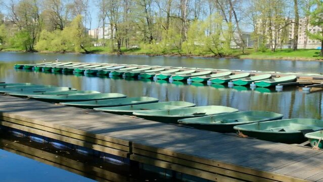 A row of boats is locked on the river, gently bobbing with the current. The boats are lined up neatly, each one painted a different color. 