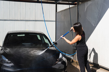 Car washing. Woman is washing her car at self service washing station.