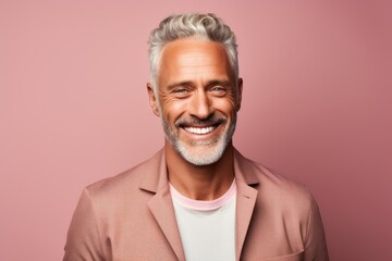 Portrait of a happy man in his 50s smiling at the camera isolated in solid pastel color wall