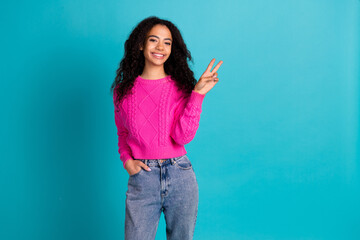 Photo of lovely young girl show v-sign empty space wear pink pullover isolated on teal color...
