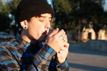 Chico joven encendiendo un cigarrillo al aire libre
