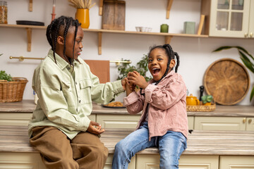 Small adorable multiethnic girls playing in kitchen enjoying weekend spending together