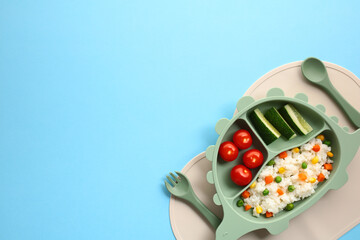 Kids meal flat lay. Colorful childrens meal on a dinosaur-shaped silicone plate with fresh veggies...