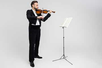 Accomplished violinist guided by sheet music performing classical music © zinkevych