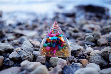 A pyramid with mineral decorative stones on the background of a river. An esoteric symbol.