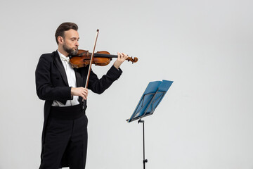 Bearded male violinist playing violin in front of sheet music