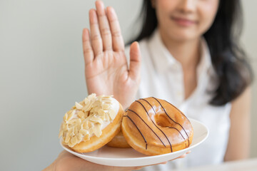 Diet concept, asian young woman hand push out, deny sugar donut, doughnut and sweet taste food on...