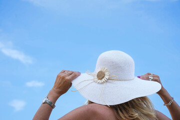 rear view of woman tourist wearing a sun hat with the blue sky. Travel destination in summer holidays