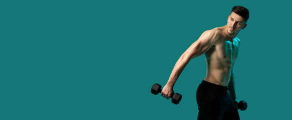 A man is lifting dumbbells while standing on a green background. He is focused and determined, with...