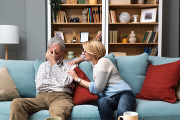 Simple living. Mature senior couple at home, woman emotional support to her husband, comfort him in...