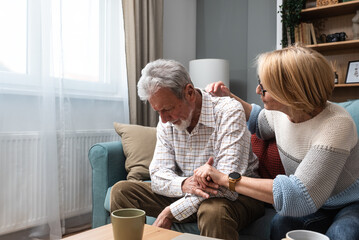 Simple living. Mature senior couple at home, woman emotional support to her husband, comfort him in...