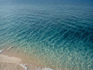 Obraz premium Gentle waves lapping against pristine sandy shore, creating serene atmosphere. Crystal clear waters reveal intricate patterns on ocean floor, while gradient of blues showcases seas depth, clarity.