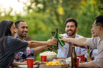 Happy friends having fun outdoor toasting beer glasses celebrating pleasant event