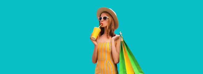 Fashion portrait of beautiful young woman with colorful shopping bags drinking juice in summer hat