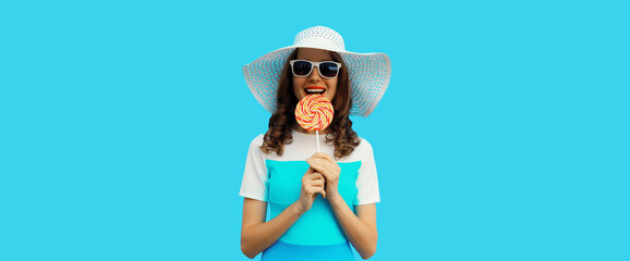 happy cheerful young woman holding colorful lollipop wearing white summer hat on blue background