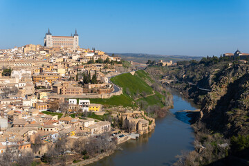 Fototapeta premium views of the impressive walled city of Toledo surrounded by the Tagus River. The imposing ancient castle Alcazar at the top.