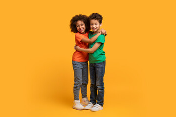 Two African American children are embracing each other warmly on a vibrant yellow background. Their...