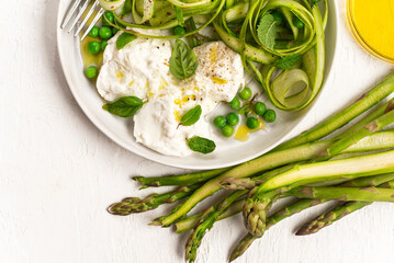 
Salad with fresh asparagus, green peas, aromatic herbs with Bufala mozzarella. Healthy summer and spring lunch Mediterranean and French cuisine, balanced nutrition. White background, close up