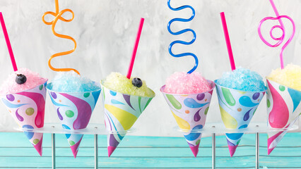 A row of colourful snow cones with crazy straws, ready for sharing.