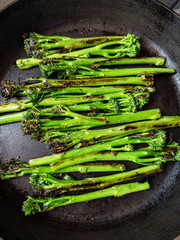 Charred broccolini spears in a black pan