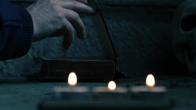 Creepy old worn book with human skull and candle bokeh
